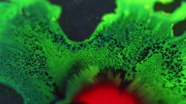 油漆滴落 墨水洒了脱色红色绿色发光液体飞溅扩散流动颗粒纹理深色抽象背景 — 图库视频影像