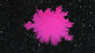 Mürekkep damlası. Boya serpintisi. Odaklanmamış neon neon pembesi rengi, koyu siyah simli parçacıklar üzerinde parlayan leke lekesi hareketi, soyut arkaplan dokusunu bokeh aydınlatma efektini ortaya çıkarır..