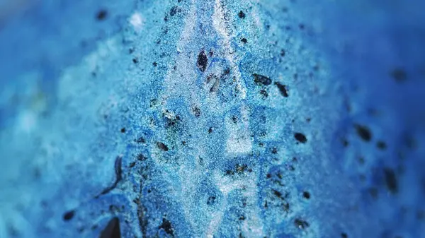 Işıldayan mürekkep arka planı. Islak pigment. Parlak akış. Parlak mavi sıvı ve siyah madde yüzeyde yayılıyor soyut bir harmanla..