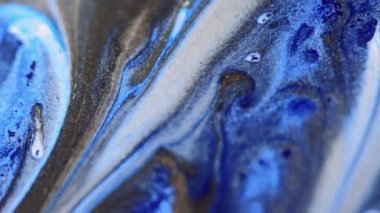 Parlak sıvı damlası. Mürekkep döküldü. Bulanık mavi bronz beyaz renkli metalik desenli boya emülsiyon dalgası hareketli büyüleyici soyut sanat arka planı.