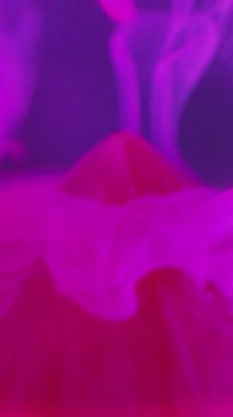 Dikey video. Mürekkep bırakma arkaplanı. Sıvı pigmenti. Soyut sis. Floresan pembe renk sıvı buharı, geometrik tasarımda kırmızı taş piramidin üzerindeki suda hareket eder..