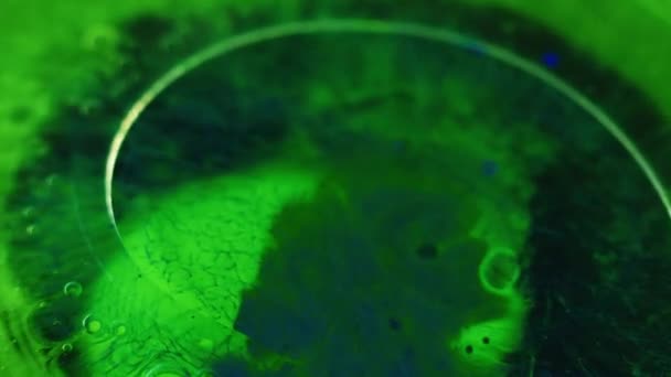 ペイントスプラッシュ オイルブロブ カラーミスト 濃縮されたネオン グリーン ブルー インク水透明なゲルの泡は黒い抽象的な芸術の背景の動きを浮かべます — ストック動画