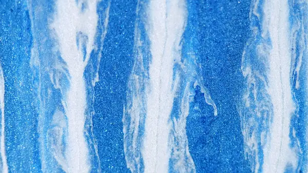 Paint drip. Glitter fluid spill. Defocused blue white color metallic shimmering texture acrylic ink emulsion flow abstract art background.