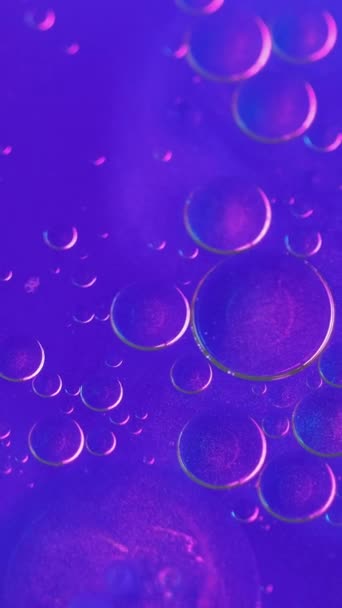 バーティカルビデオ オイルバブルの背景 光沢のある液体塗料 蛍光ピンクブルーの輝くインクで広がる透明な汚れ 抽象的なブレンド 輝く放射性物質 — ストック動画