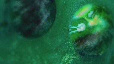 Işıldayan boya arka planı. Parlak pigment. Dekoratif sıvı karışımı. Siyah gümüş kıvrımlar soyut, parlak yeşil bir maddeyle yağ baloncuğuna yayılıyor. Büyüleyici bir sanat eseri..