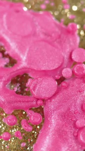 バーティカルビデオ 抽象的な背景 液体塗料ミックス グリッターインクバブル アクリルスプラッターデザインアートのスパークリングゴールドボトムで表面に輝く美しいトレンディなピンクの輝く流体スポット — ストック動画