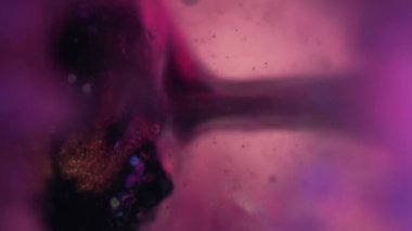 Jel yağı damlası. Mürekkep kabarcığı. Serum emülsiyon dokusu. Odaklanmamış neon pembe mavi siyah simli ıslak boya damlası hareketli sanat soyut arkaplan.