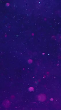 Dikey video. Bokeh ışıkları. Soyut odaklanmış parlaklık. Su altı ışıltısı. Bulanık, yuvarlak, ışıldayan parçacıklar hipnotik arka plan sanatında koyu mavi su derinliğinde yüzüyorlar..