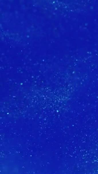 バーティカルビデオ バックグラウンド 割り当てられたグリッター 水中フロー クリエイティブなボケの液体抽象芸術で青い水に広がる白い輝くシマーの渦 — ストック動画
