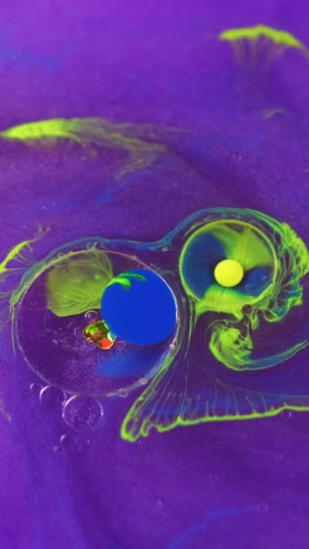 垂直录像 摘要背景 油漆混合气泡 五颜六色的油水闪烁着紫罗兰光芒的明亮的黄色蓝滴的运动与凝聚素液体催眠创造性液体艺术 — 图库视频影像
