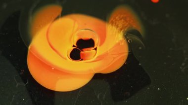 Boya sıçraması. Yağ damlası. Renk sisi. Odaklanmamış turuncu mürekkep karışımı su kabarcıkları siyah parçacıkların dokusunda akış hareketi soyut sanat arkaplanı.