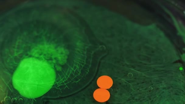 ペイントスプラッシュ 流体バブル インク水 不分割された緑色のオレンジ色のエマルジョンミックスドロップレット円 黒の抽象的なアートの背景に浮かぶ動き — ストック動画