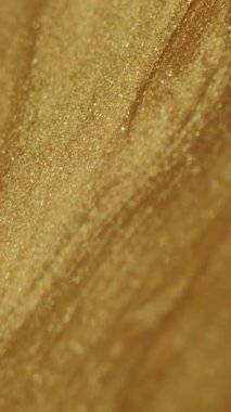 Dikey video. Altın akışkan. Parlak boya dalgası. Odaklanmamış parlak sarı metalik renk parçacıkları yeşil sanat soyut arka planında doku mürekkebi akışı.