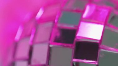 Dikey video. Disko arka planı. Ayna küresi. Güzel kulüp gümüş yansıma topu kare elementleri neşeli atmosferde pembe ışıkta dönüyor.