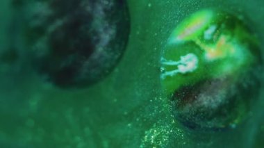 Işıldayan boya arka planı. Parlak pigment. Dekoratif sıvı karışımı. Siyah gümüş kıvrımlar soyut, parlak yeşil bir maddeyle yağ baloncuğuna yayılıyor. Büyüleyici bir sanat eseri..