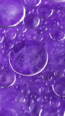 Dikey video. Soyut arkaplan. Işıldayan sıvı mürekkep. Kabarcık yüzeyi. Neon menekşe içinde yüzen hava küreleri dinamik sanatta kaynayan parlak su etkileri.