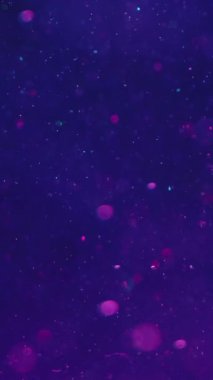 Dikey video. Bokeh ışıkları. Soyut odaklanmış parlaklık. Su altı ışıltısı. Bulanık, yuvarlak, ışıldayan parçacıklar hipnotik arka plan sanatında koyu mavi su derinliğinde yüzüyorlar..