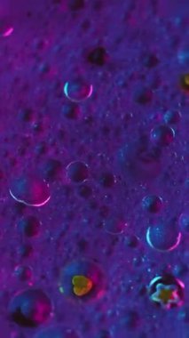 Dikey video. Mürekkep karıştırma arkaplanı. Parıltılı boya. Akışkan pullar sanat eseri. Mor mavi renkli sıvı hava kabarcıkları boyada parıldayan parçacıklar soyut hipnotik akışı harmanlıyor.