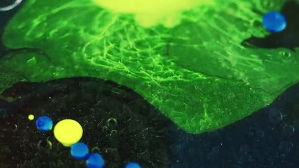 バブルを塗る オイルスプラッシュ 濃い黒の抽象的な芸術の背景に浮遊動きを混合するネオン グリーン ブルー 黄色のアクリル インク 染料水の混合ゲル ドロップレット球 — ストック動画