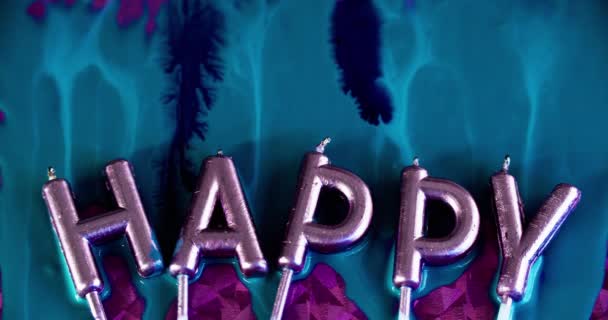 バースデーキャンドル ハッピーホリデー ペイントドリップ ピンクの表面の抽象的な芸術の背景の青い色のインク流出の流れが付いている虹彩の光のライトの金属の光沢のあるワックスの手紙 — ストック動画