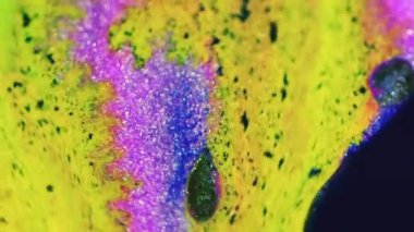 Parlak mürekkep damlası. Boya akışı. Parlak neon sarısı mavi renk parıldayan parçacıklar dokusu sıvı sızıntısı karışık hareket soyut sanat arka planı.