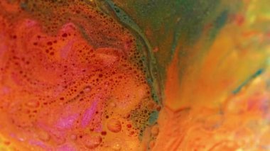 Dikey video. Soyut arkaplan. Sıvı boya karışımı. Işıldayan akış. Renkli kontrast sarı yeşil turuncu kabarcıklar doku sıvısı suya yayılıyor yaratıcı sanatta ışıltılı taban.