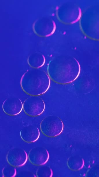 垂直录像 摘要背景 气泡是液体 油腻的表面在具有创意魅力的艺术中 在霓虹灯蓝色闪光的水中流动着的脂肪滴圆圈 — 图库视频影像