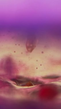 Dikey video. Jöle baloncukları. Jel yağı damlası. Mürekkep suyu. Odaklanmamış neon mavisi pembe renk köpük sıvı boya köpük dalga hareket sanatı soyut arkaplan.