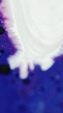 Dikey video. Mürekkep arkaplanı. Renk sıvısı karışımı. Parıltı dalgası. Büyüleyici hipnotik makro soyut tasarım fantezi sihirli sıvı sanatında siyah noktalı parlak mavi beyaz boya.