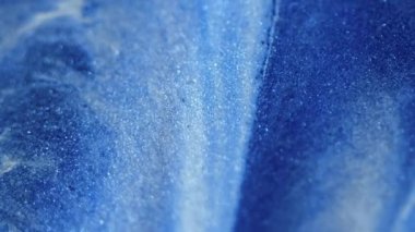 Parıltılı boya akışı. Işıldayan doku. Kar çağlayanı. Odaklanmamış mavi beyaz renk parlayan mürekkep emülsiyonu hareket soyut sanat arkaplanı.