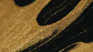 Parıltılı boya döküldü. Sıvı arkaplan. Köpüklü sıvı. Altın siyah renkli titreşimli parçacıklar mürekkep damlaları soyut sanat dokusuna damlıyor.