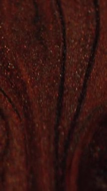 Dikey video. Islak sim akışı. Mürekkep akıyor. Bulanık kahverengi renk, parıldayan parçacıklar, boya, sıvı su, harmanlanmış hareket, karanlık, soyut sanat arka planı..