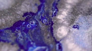 Boya damlası. Parlak sıvı sıçraması. Odaklanmamış mavi gümüş rengi parlayan parlak desen mürekkep parlatıcısı sıçratma karışık hareket soyut sanat arkaplanı.