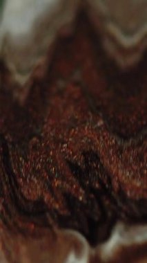 Dikey video. Parıldayan sıvı. Mürekkep akıyor. Odaklanmamış kahverengi bronz beyaz siyah renk parıldayan mermer desen akrilik boya sızıntısı soyut sanat arka planı.