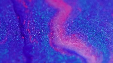 Parlak doku. Boya akışı. Odaklanamayan mavi pembe renkli parıldayan parçacıklar, soyut sanat arka planında hafif mürekkep hareketini bozuyor..