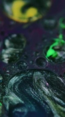 Dikey video. Mürekkep karıştırma arkaplanı. Parıltılı boya. Akışkan pullar sanat eseri. Metalik siyah, beyaz, yeşil, yeşil, sıvı yağ kabarcıkları mor, ışıldayan parçacıklar boya, soyut hipnotik girdapları harmanlıyor..