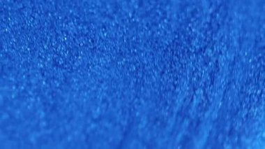 Parıldayan sıvı dökülmüş. Pırıl pırıl. Odaklanmamış mavi renk parıldayan parlak parçacıklar boya dalgaları kademeli hareket soyut sanat arkaplanı.