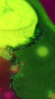 Neon akışkan dalga. Boya karıştırılmış su. Parlak yeşil, parlak, pembe, simli, desenli mürekkep damlası akış sanatının soyut arka planı.