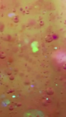 Dikey video. Köpük sıvısı. Yağ dokusu. Mürekkep damlası. Odaklanmamış sarı pembe renk yarı şeffaf parlatıcı ıslak jel boya oksijen küresi yüzen hareket sanatı soyut arka plan.