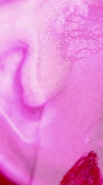 Dikey video. Işıldayan mürekkep arka planı. Islak pigment. Parlak akış. Kırmızı yüzeye yayılan parlak beyaz sıvı madde soyut dalga şeklinde yayılır..