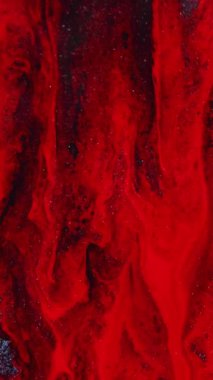 Dikey video. Parlak mürekkep arka planı. Boya karışımı. Işıl ışıl dökülüyor. Parlayan kırmızı siyah tanecikler doku sıvı damla dalgası hipnotik soyut sanatta metalik yüzeye yayılıyor..