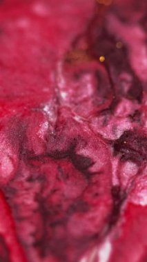 Dikey video. Soyut arkaplan. Parıltılı boya. Parlak sıvı karışımı. Canlı kırmızı bordo rengi mürekkep parıldayan parçacıklar tahıl dokusu boya dalgası kare yüzeyde yayılıyor..