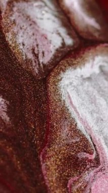 Dikey video. Parlak sıvı arka plan. Mürekkep akışı. Köpüklü karışım. Pembe kahverengi beyaz renkte parıldayan boya, yüzeydeki akış hareketini soyut büyüleyici fantezi sanatıyla harmanlıyor..