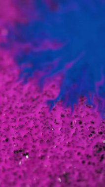 Dikey video. Mürekkep damlası. Boya serpintisi. Odaklanmamış mavi pembe lekeli lekeler tahıl bokeh hafif dokusuna yayılıyor soyut arkaplan efekti ortaya çıkarıyor.