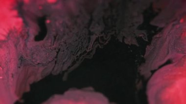 Parlak bir dökülme. Boya sıvısı. Bulanık siyah kırmızı renk parıltılı kum parçacıkları akrilik akışkan su pigmenti karışımı emülsiyon akışı hareketli soyut sanat arka planı.