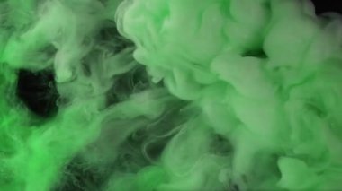 Parıltılı boya suyu. Duman bulutu. Odaklanmamış yeşil renkler ışıl ışıl parçacıklar. Siyah soyut sanat arka planında sis dalgası hareketi..