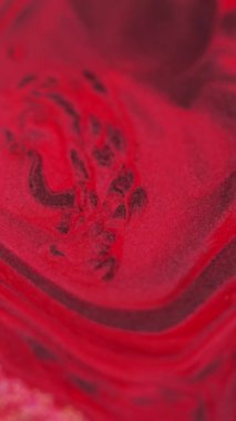 Dikey video. Mürekkep arkaplanı. Parıltılı boya. Renk sıvısı karışımı. Büyüleyici hipnotik makro soyut tasarım kırmızı bordo pigmentleri kare yüzeyde fantezi sihirli sıvı sanatla akıyor..
