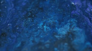Parlak sıvı. Parlak mürekkep döküldü. Odaklanmamış mavi renk ışıl ışıl tanecikler akrilik boya akışkan su pigmenti karışık akış hareketi soyut sanat arka planı.