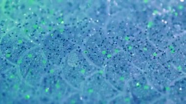 Parlak sıvı damlası. Parlak jel dokusu. Mavi bulanık renk parıltılı pullu tanecikler yarı şeffaf sıvı su emülsiyonu hareketli soyut sanat arka planı ve Bokeh ışıkları.