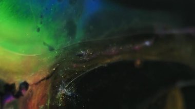 Renk jeli sıvısı. Parıltılı boya karışımı. Odaklanmamış kırmızı mavi yeşil gradyan ışıl ışıl parçacıklar. Siyah soyut sanat arka planında yüzen mürekkep lekesi dokusu..